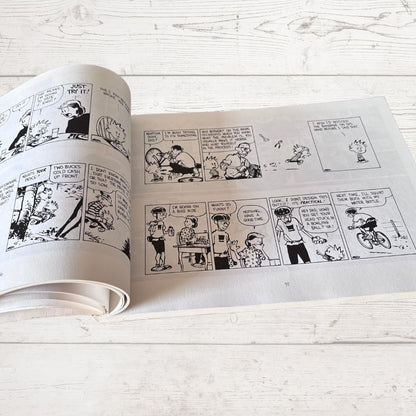 Open comic book with black and white illustrations on a light wooden surface