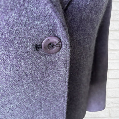 Close-up of a textured purple coat with a button on a light background