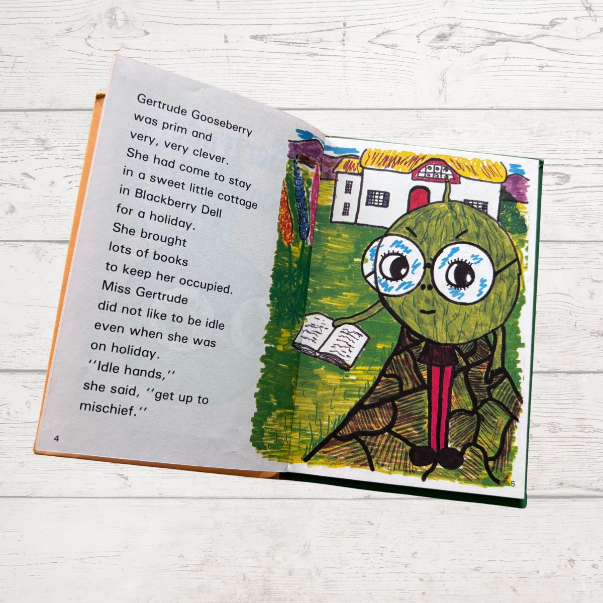 Open book with a leaf character illustration on a wooden surface