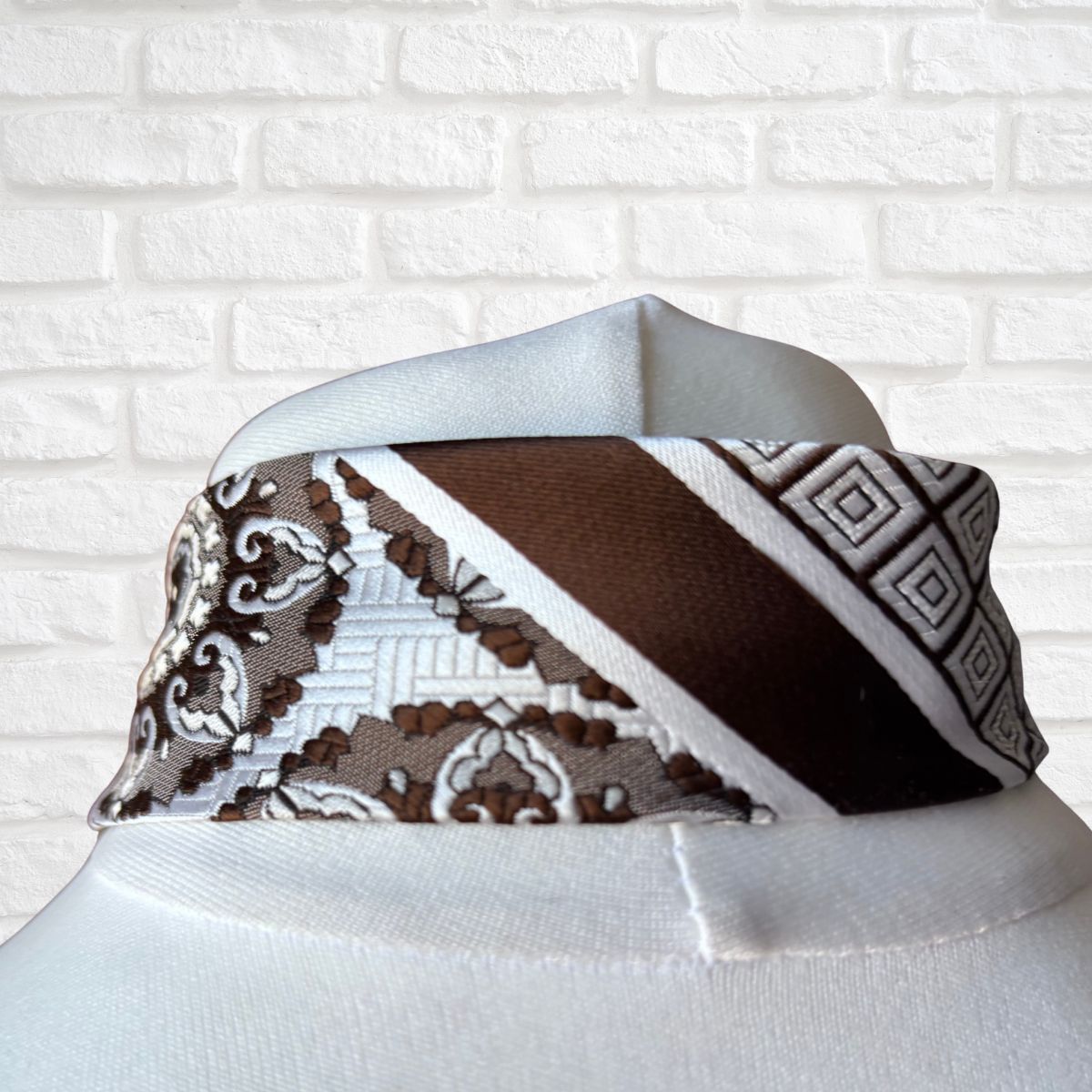 patterned tie against a white brick wall background