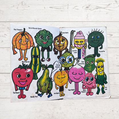 Colorful illustrated book open to pages with cartoon vegetables on a wooden surface