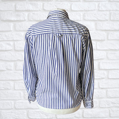 Blue and white striped shirt on a mannequin against a white brick wall.