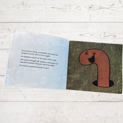 Open book with a cartoon worm illustration on a wooden surface