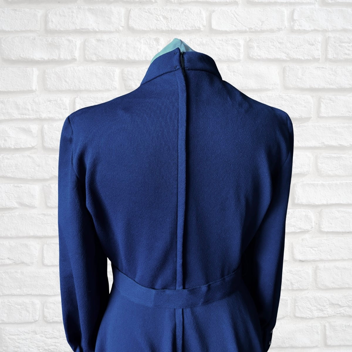 Blue dress on a mannequin against a white brick wall background