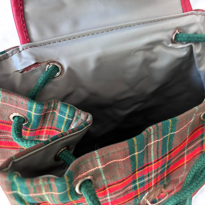 Close-up of a plaid bag with drawstrings and a grey  interior.
