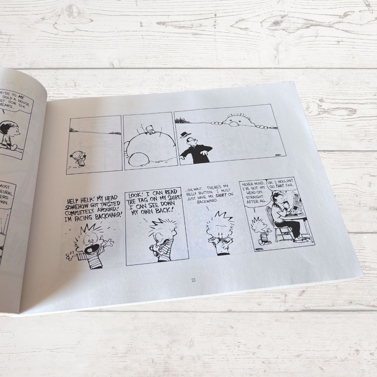 Open comic book with black and white illustrations on a light wooden surface
