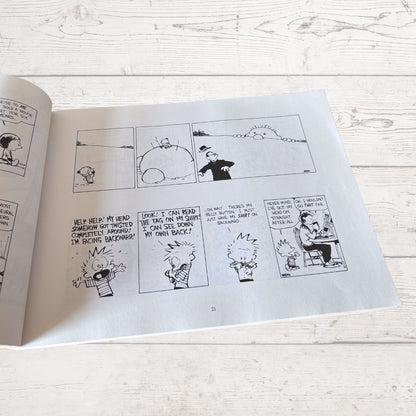 Open comic book with black and white illustrations on a light wooden surface