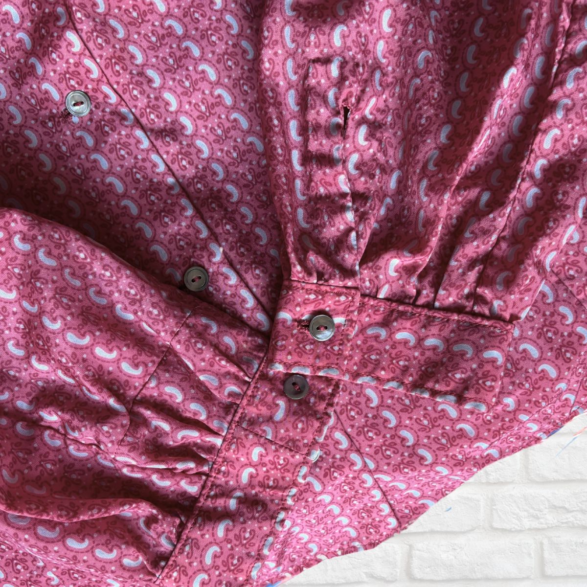 Close-up of the cuffs pf pink and grey  patterned shirt with buttons on a white background
