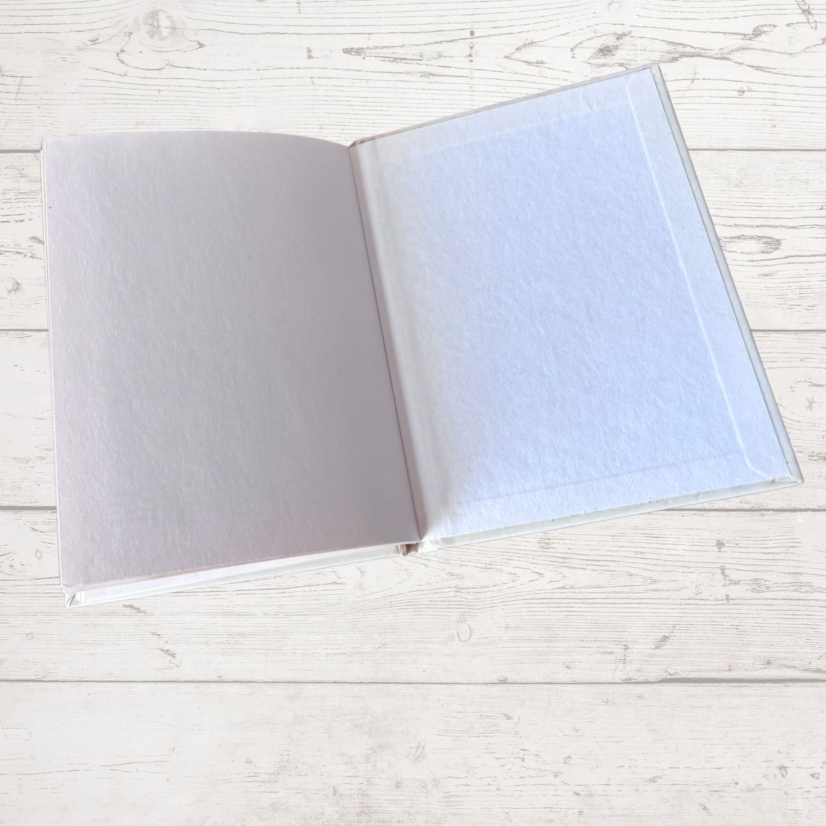 Open notebook with light blue cover on a white wooden surface