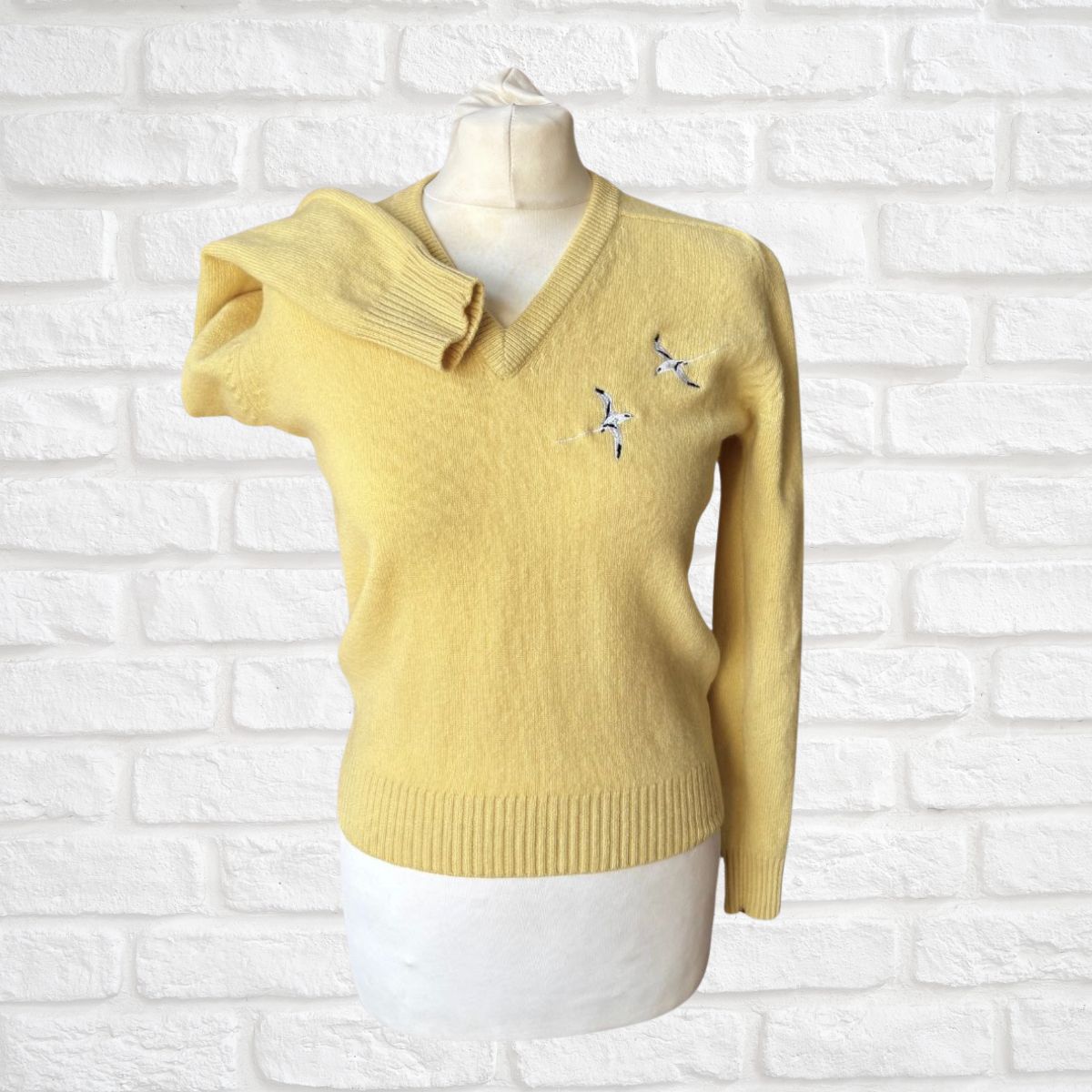 Yellow sweater on a mannequin against a white brick wall background
