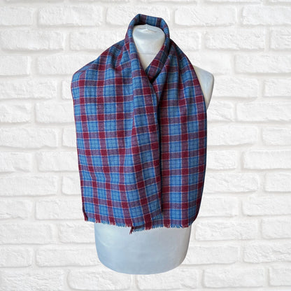 Blue and red plaid scarf on a mannequin against a white brick wall.