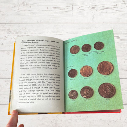 Open book with illustrations of coins on a white wooden surface