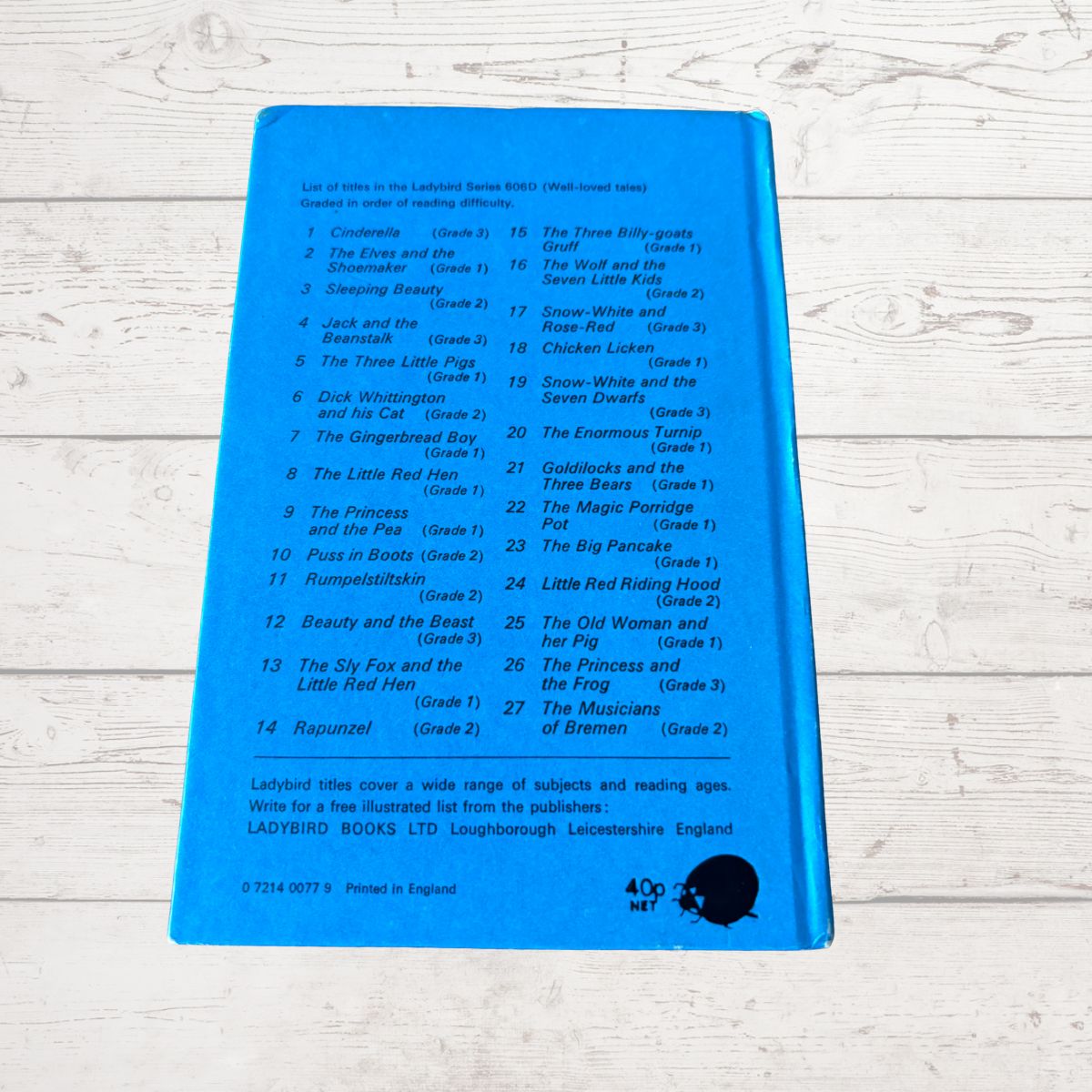 A blue back cover of a Ladybird Books children's book showing a printed list of included Little Birds series titles, photographed on a white painted wood surface.