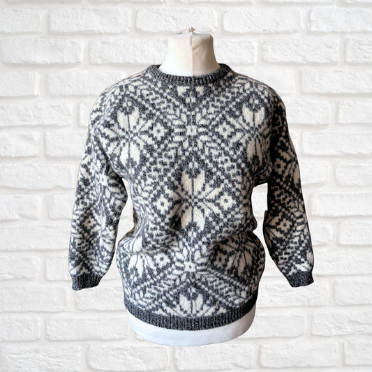 Gray and white patterned sweater on a mannequin against a white brick wall.