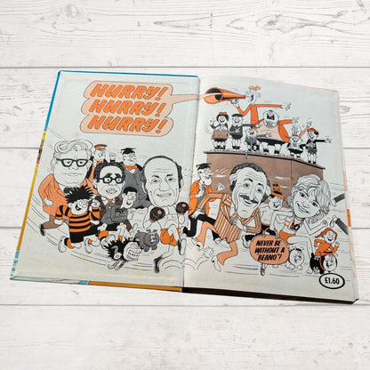 Comic book open to a page with cartoon characters and text on a wooden surface