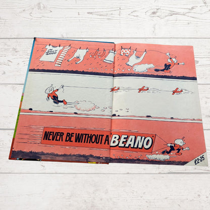 Open comic book with cartoon characters on a wooden surface, featuring 'Beano' branding.