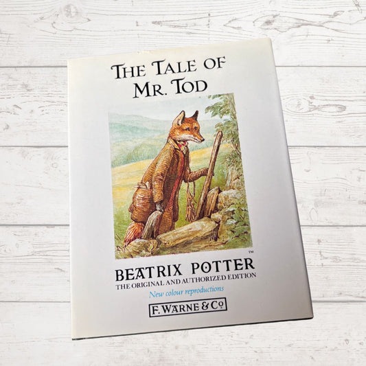 Book cover of 'The Tale of Mr. Tod' by Beatrix Potter on a wooden surface