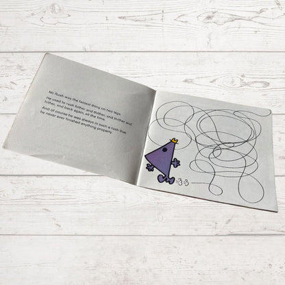 Open book with a drawing of a purple triangle character and text on a wooden surface