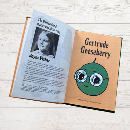 Open book with a character named Gertrude Gooseberry on a wooden surface