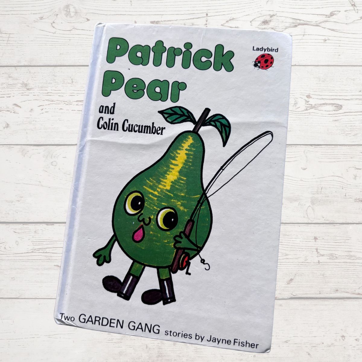 Book titled 'Patrick Pear and Colin Cucumber' with a cartoon pear character on a light wooden surface.