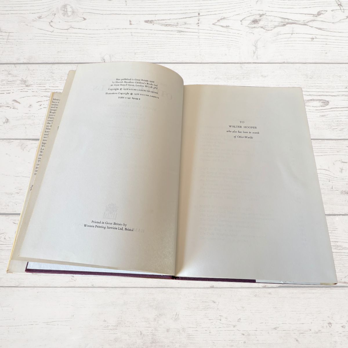 An open book laid flat on a white wood plank surface, showing printed text on both pages..