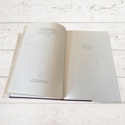 An open book laid flat on a white wood plank surface, showing printed text on both pages..