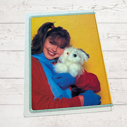Person holding a white teddy bear with a yellow background