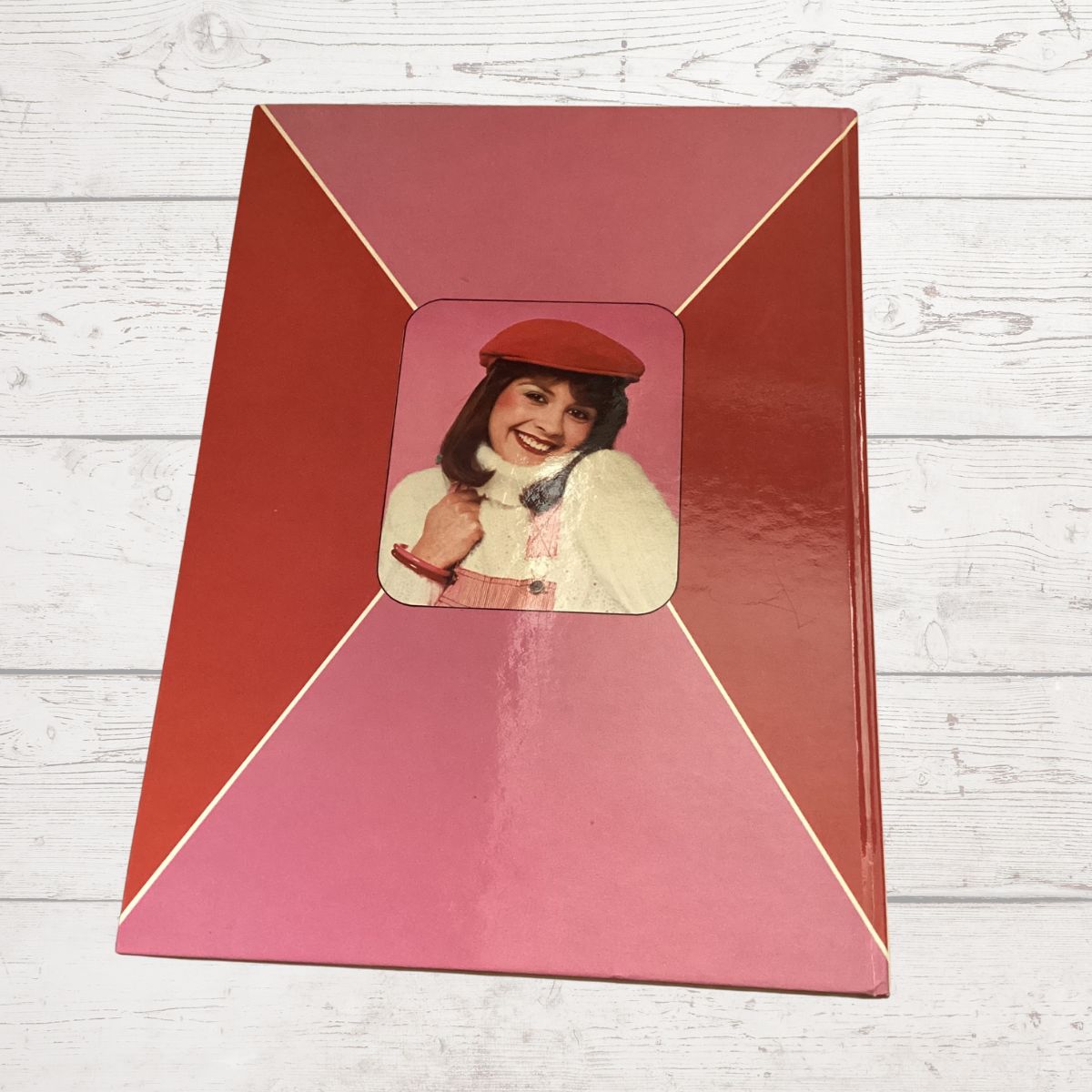 Red frame with a smaller inset photo of a woman on a wooden surface