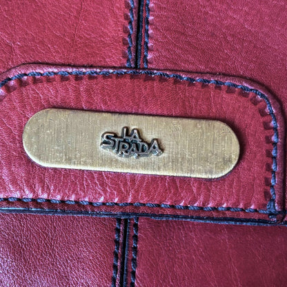 Close-up of a red leather product with 'La Strada' brand logo.