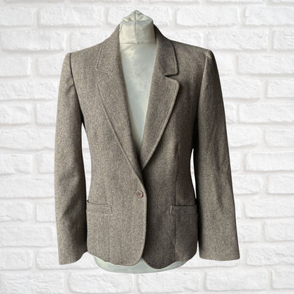 Gray /brown blazer on a mannequin against a white brick wall background