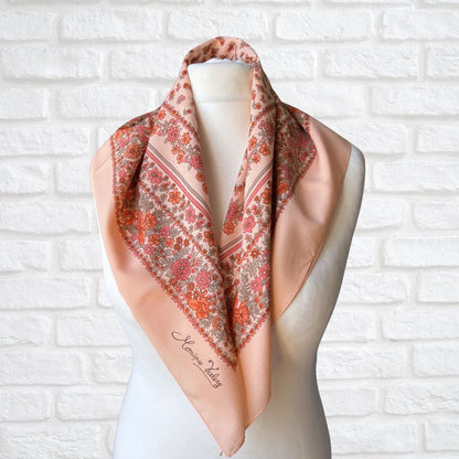 Floral patterned scarf on a mannequin against a white brick wall background