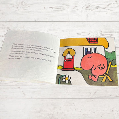 Open book with a colorful illustration of a character in front of a house on a wooden surface