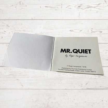 Open book titled 'MR. QUIET' by Roger Hargreaves on a light wooden surface.