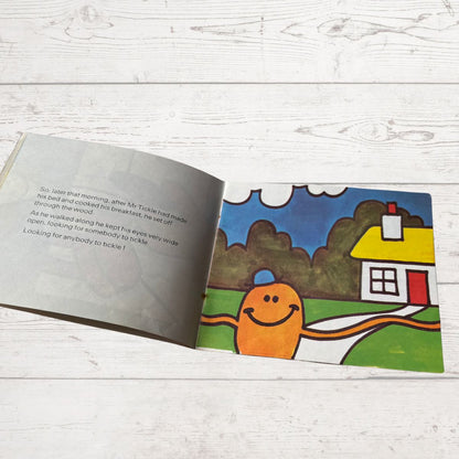 Open book with a cartoon character and house illustration on a wooden surface