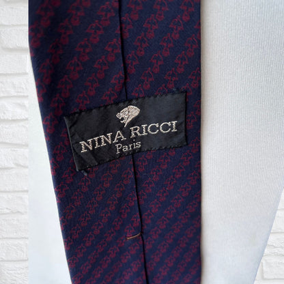 Nina Ricci label on a patterned tie against a light background