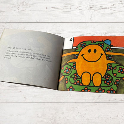 Open book with a colorful illustration of a smiling character on a wooden surface
