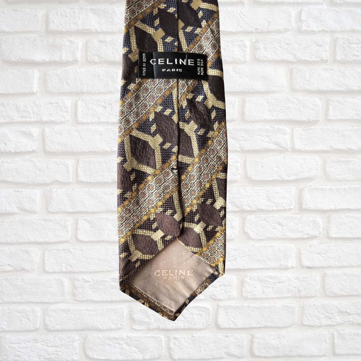 Vintage Celine patterned tie on a white brick wall background