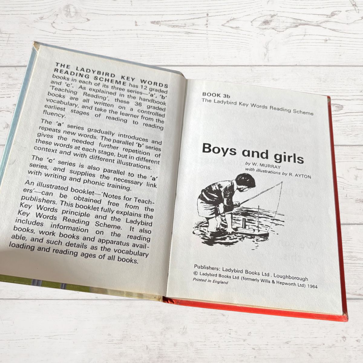 Open book titled 'Boys and girls' from The Ladybird Key Words Reading Scheme on a wooden surface.