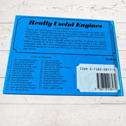 Back cover of a book titled 'Really Useful Engines' by Christopher Awdry on a wooden surface.