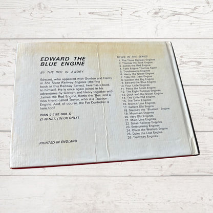 Open book showing text about 'Edward the Blue Engine' by W. Awdry on a wooden surface.