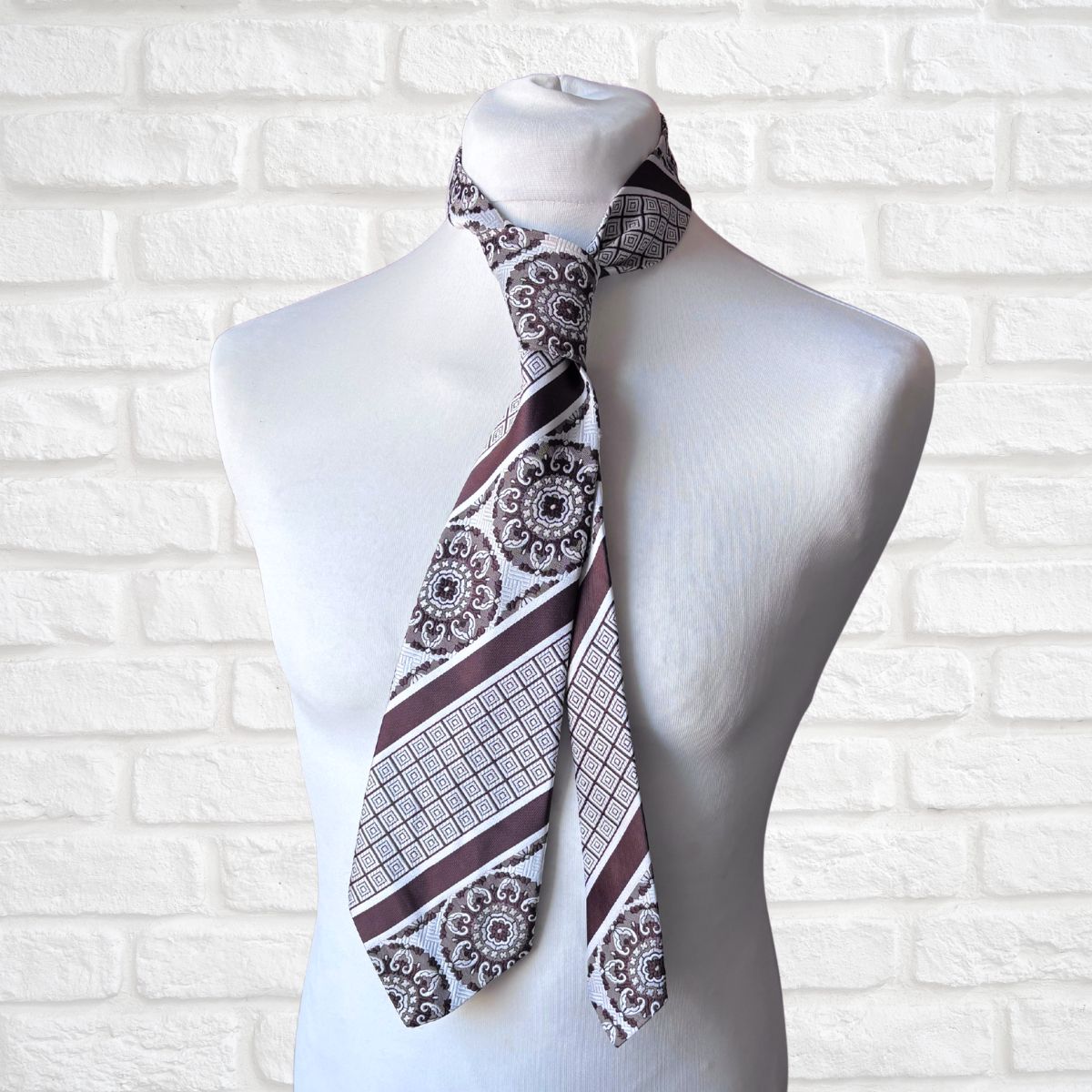Patterned necktie on a mannequin against a white brick wall background