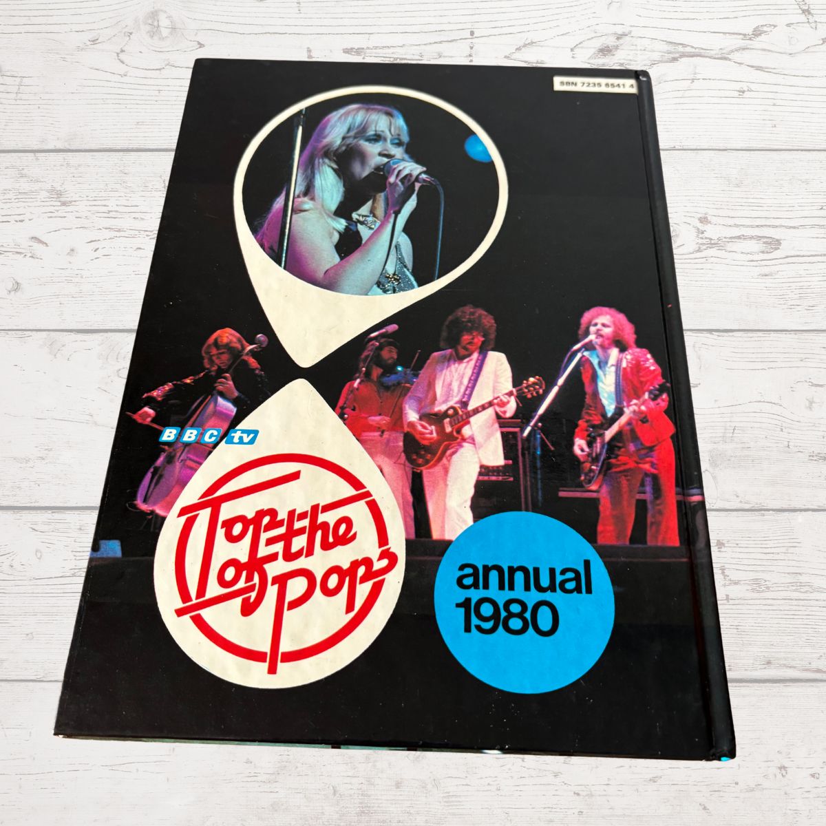 Top of the Pops annual 1980 book cover with band members and logo on a wooden surface