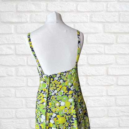 Mannequin wearing a floral dress against a white brick wall.