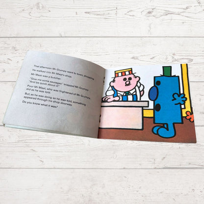 Open book with cartoon characters on a wooden surface