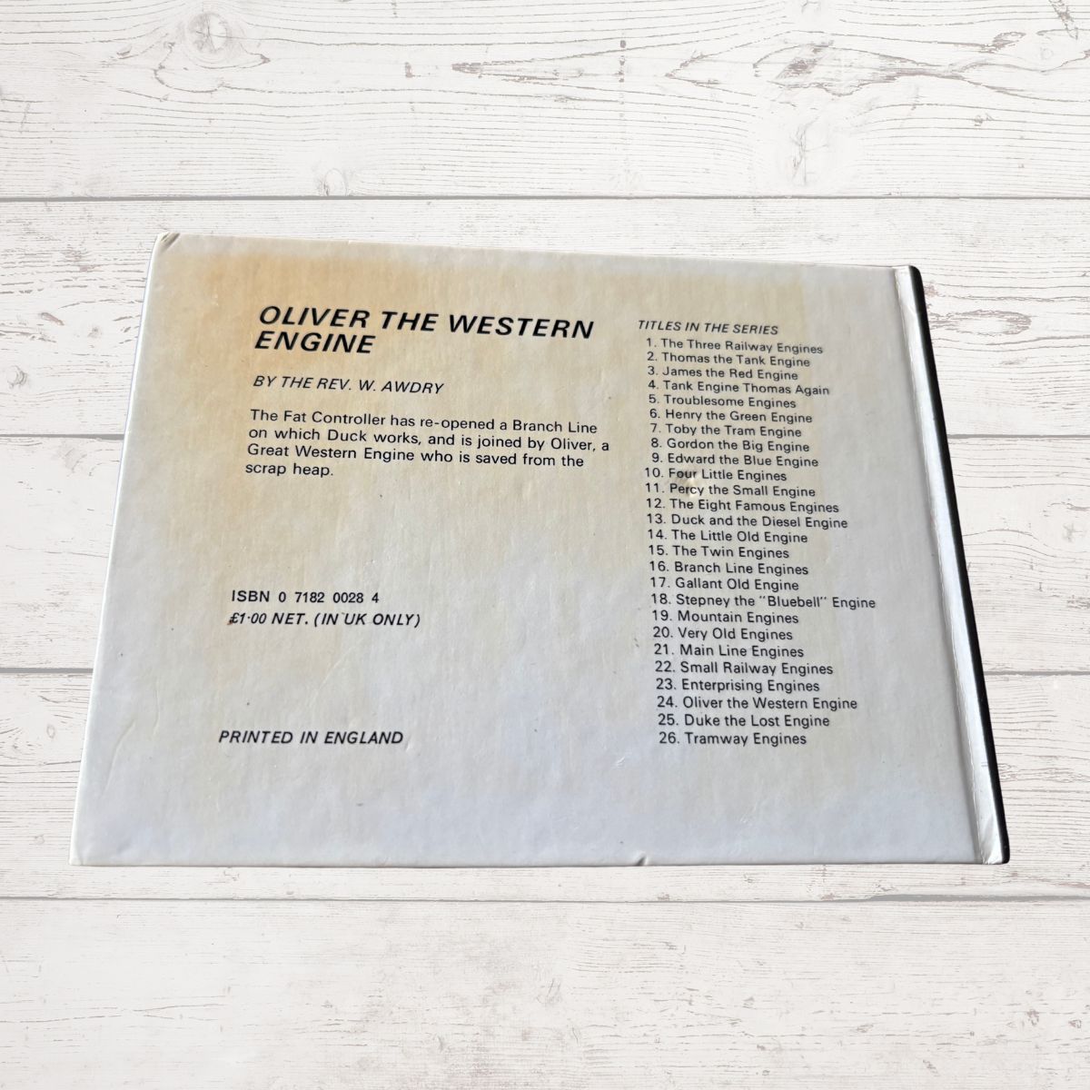 Back cover of a book titled 'Oliver the Western Engine' with text on a wooden surface.