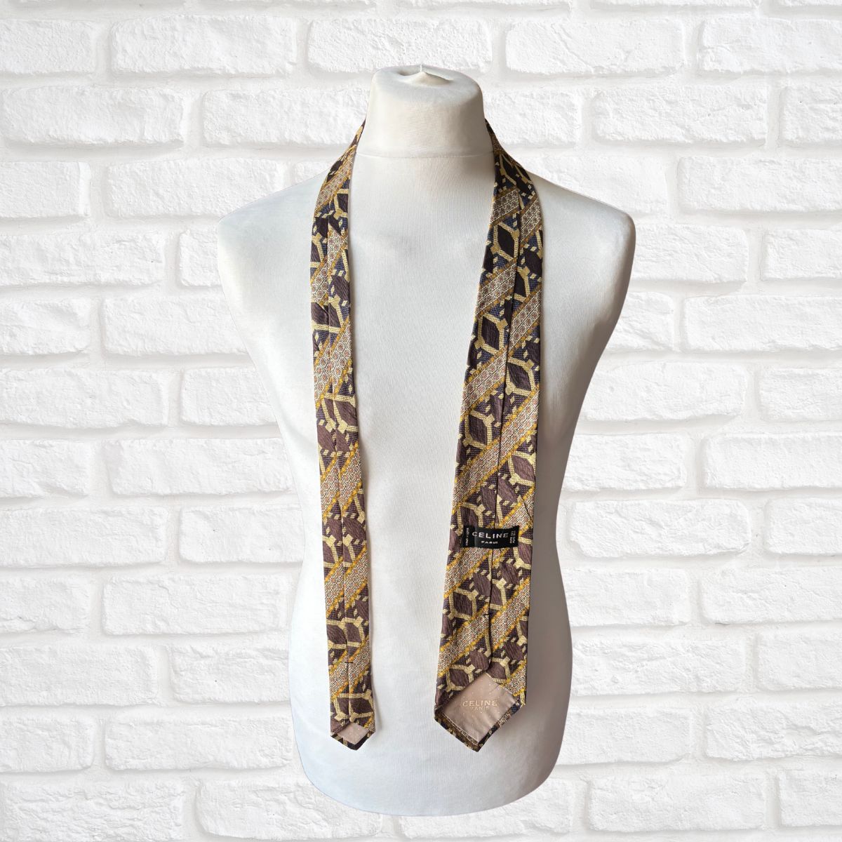 Mannequin wearing a patterned tie against a white brick wall