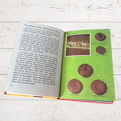 Open book with green cover featuring images of coins on a wooden surface