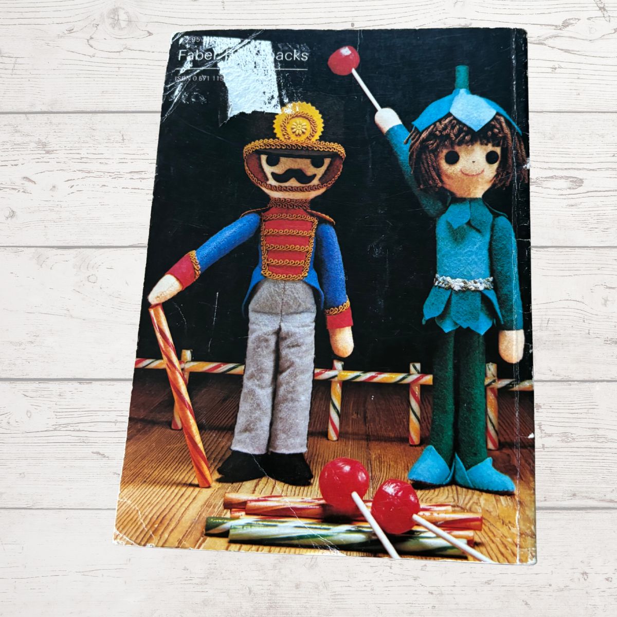 Two toy figures with colorful outfits on a wooden floor, with a black background.