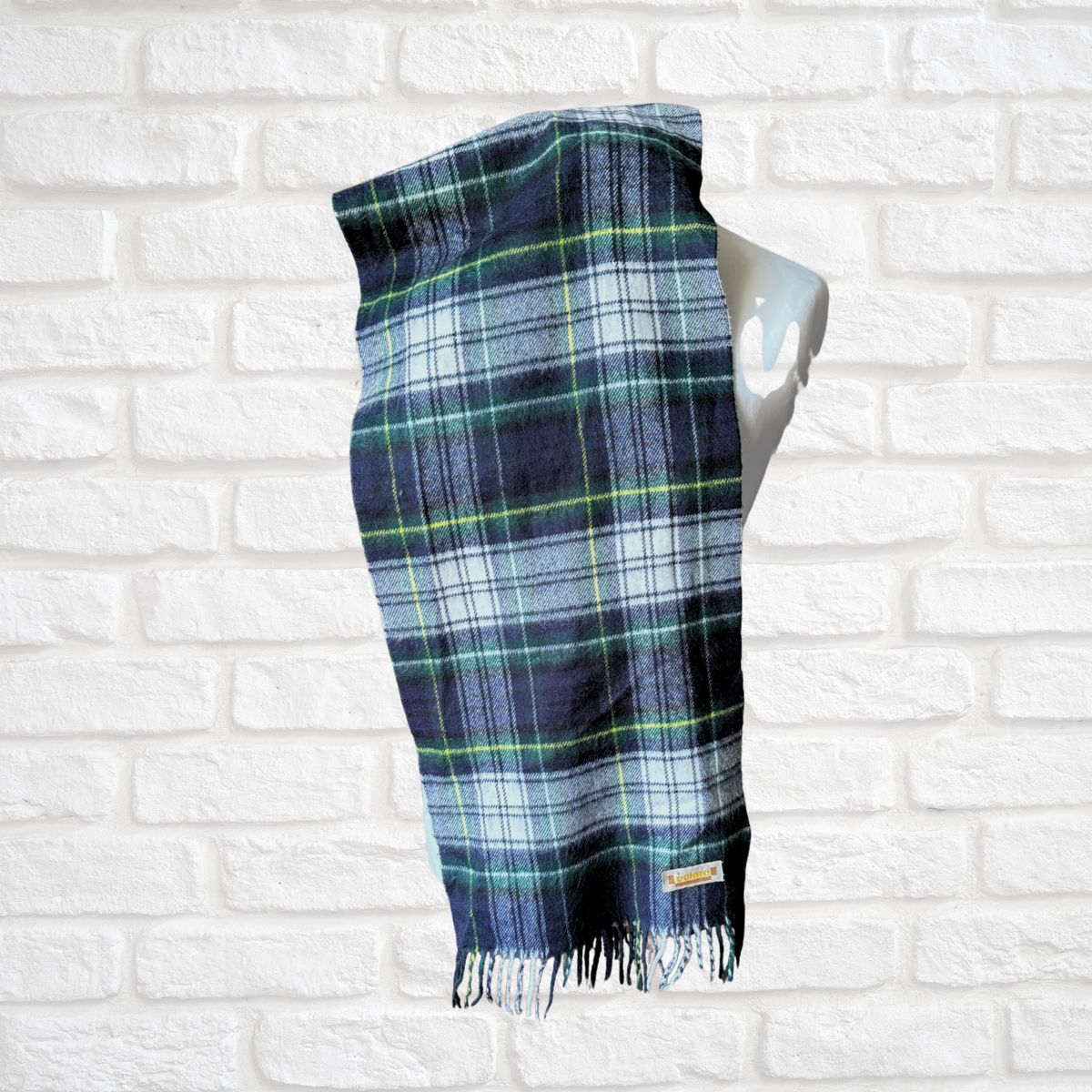 Plaid scarf on a mannequin against a white brick wall background