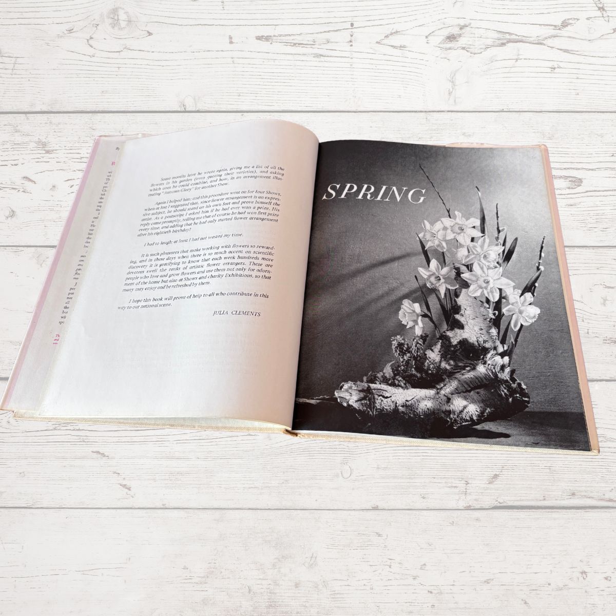 Open book on a wooden surface with a black and white photograph of flowers and the word 'Spring'.
